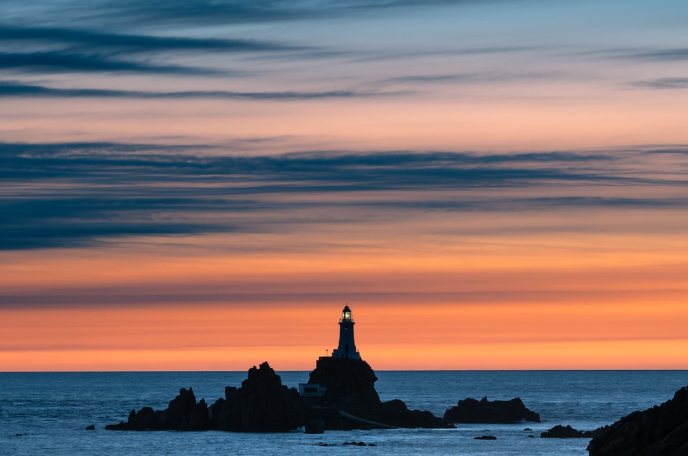 a lighthouse on a rocky outcropping at sunset