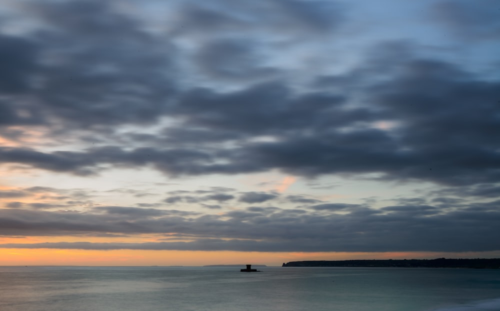 a boat is out on the water under a cloudy sky