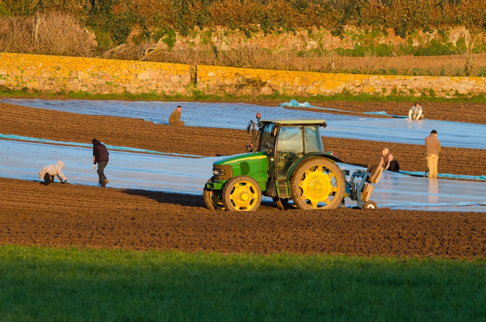 a tractor is plowing a field with people nearby