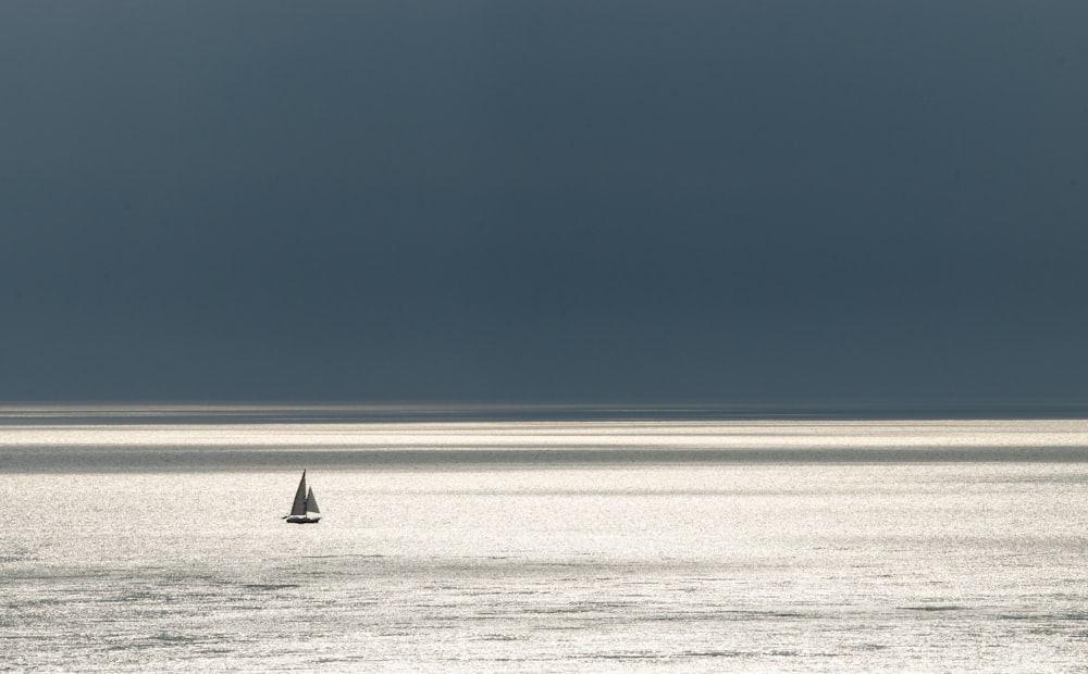 a lone sailboat in the middle of a large body of water