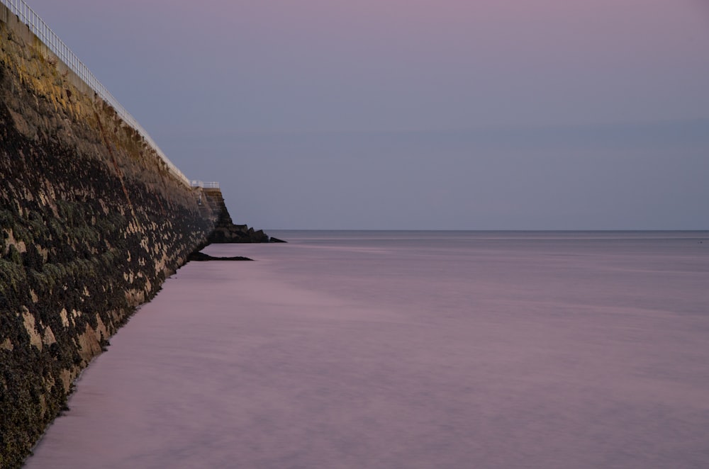 a stone wall next to a body of water