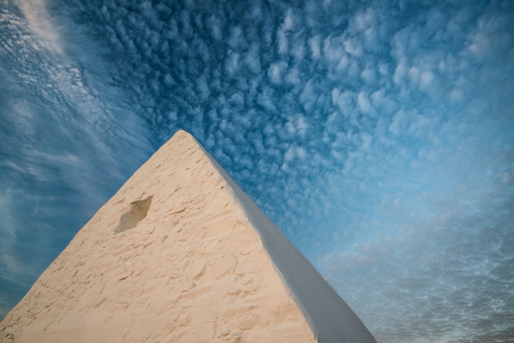 a very tall white pyramid under a cloudy blue sky