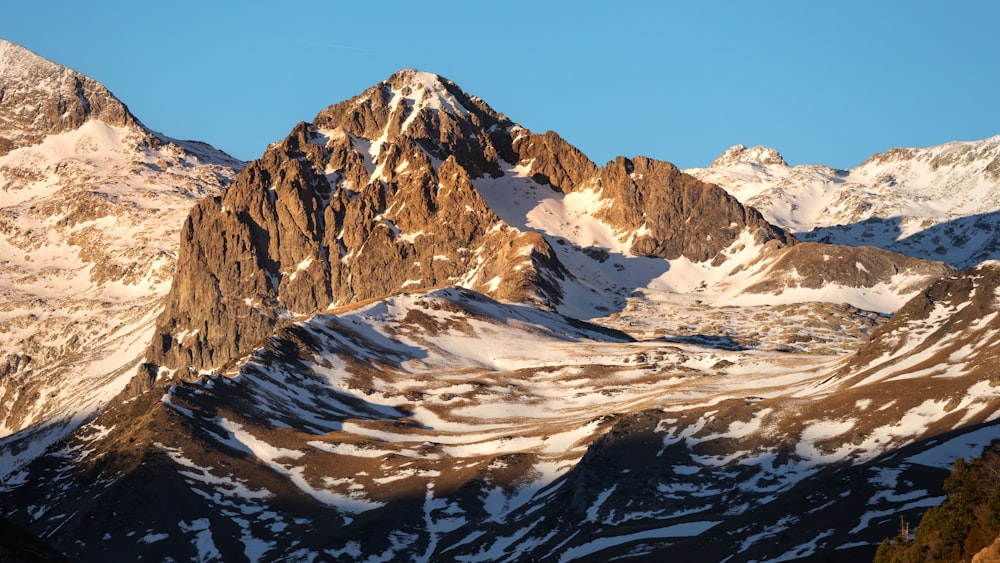 a snow covered mountain range with a blue sky in the background