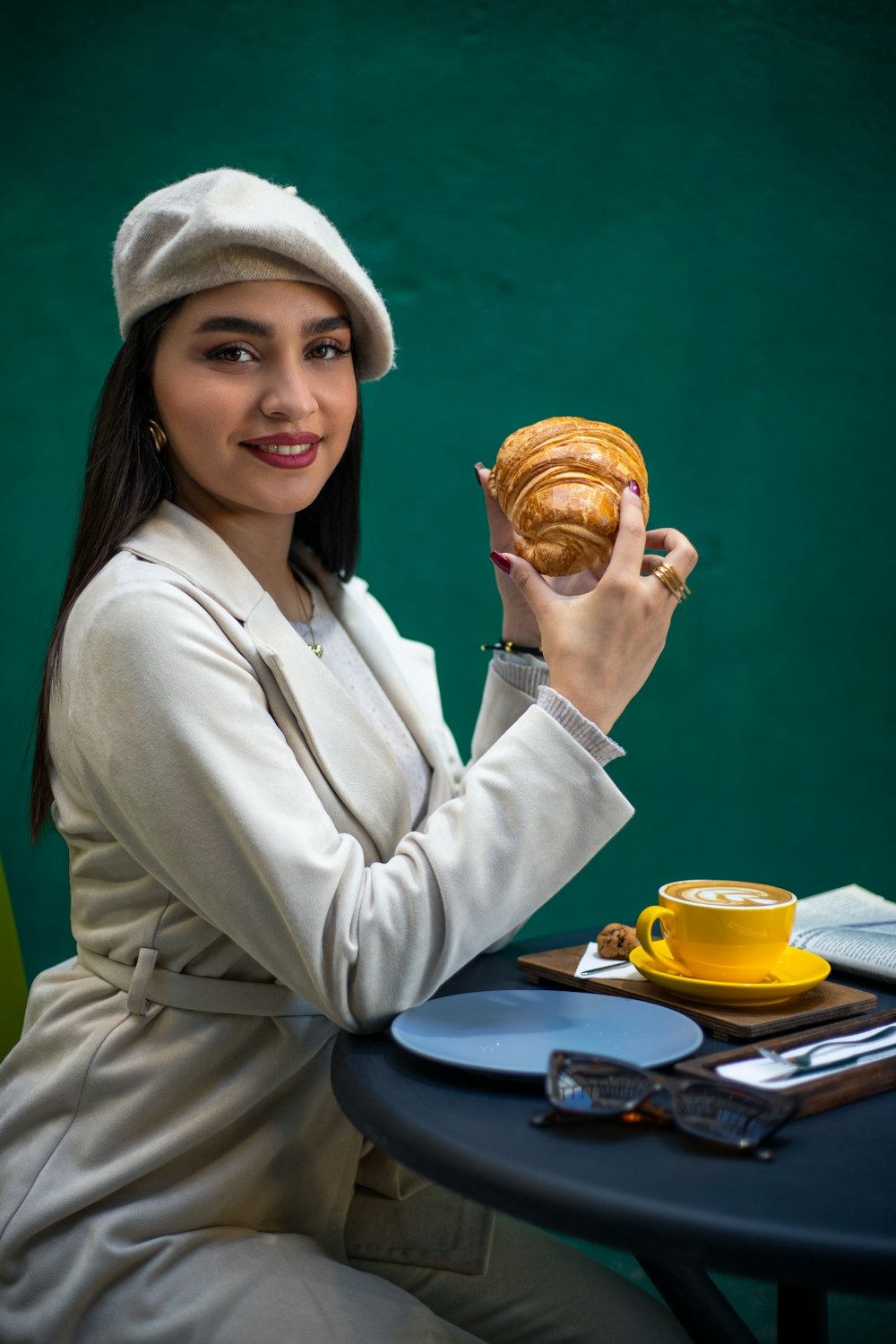 a woman sitting at a table holding a pastry