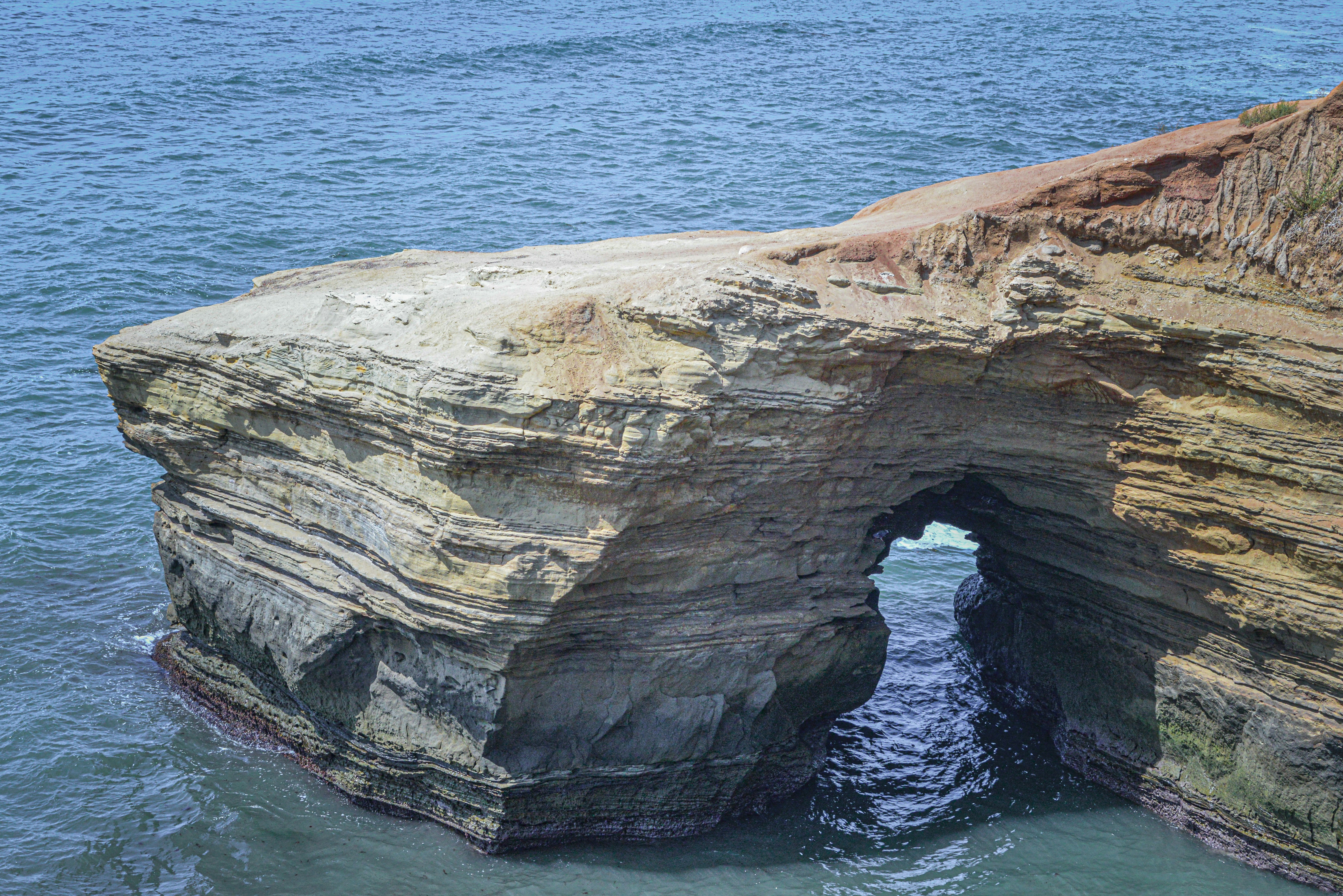 A large rock formation in the middle of a body of water photo – Free ...