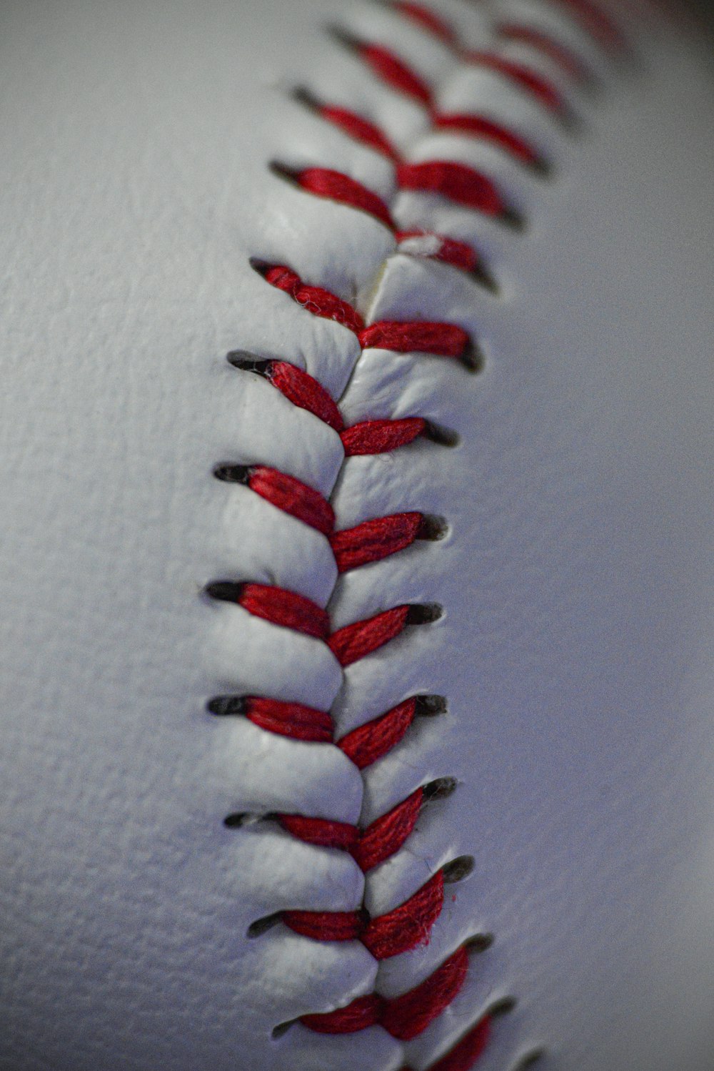 a close up of a baseball with red stitches
