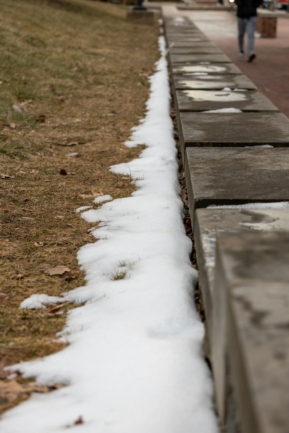 a person walking down a sidewalk next to snow