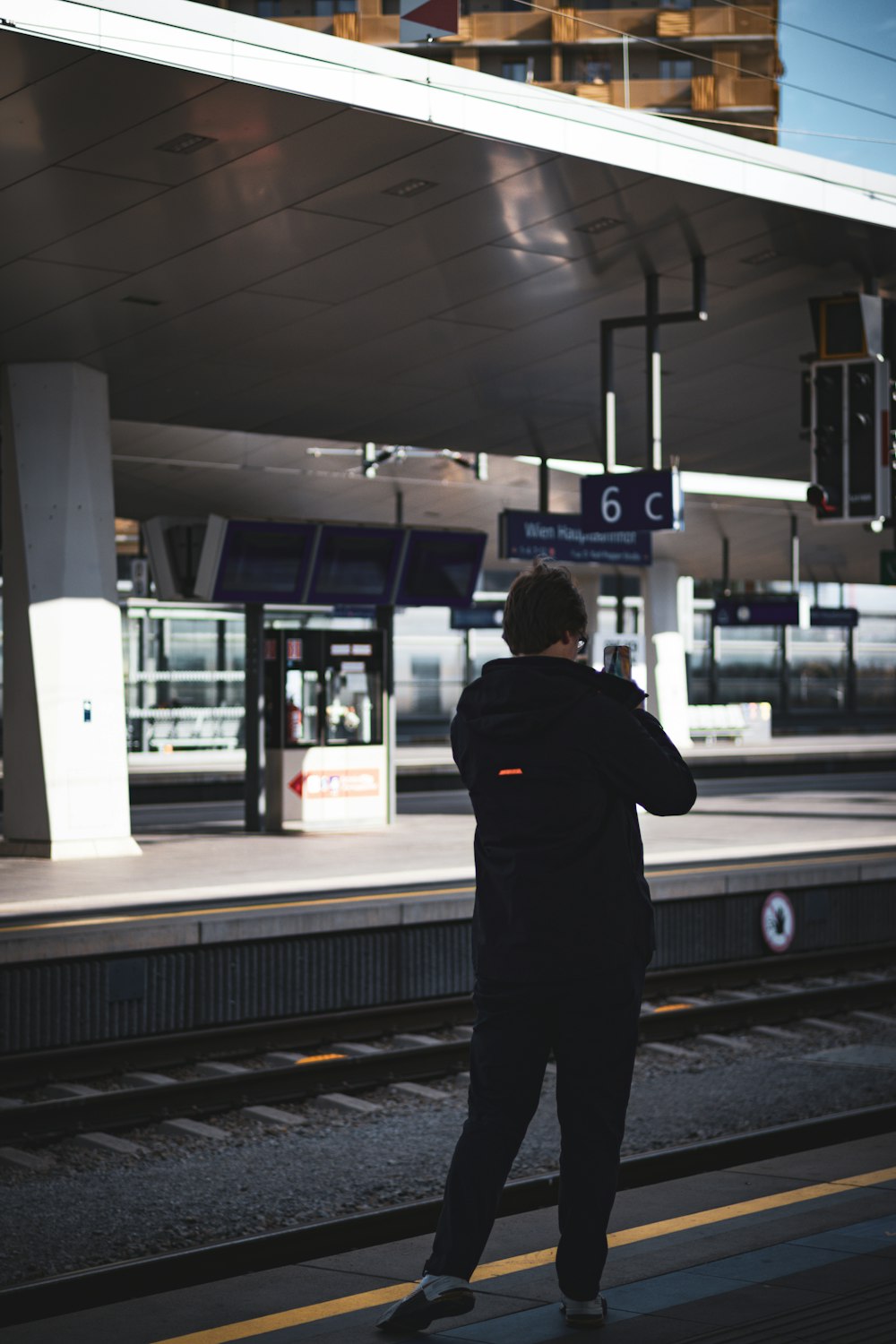 a man standing at a train station waiting for a train