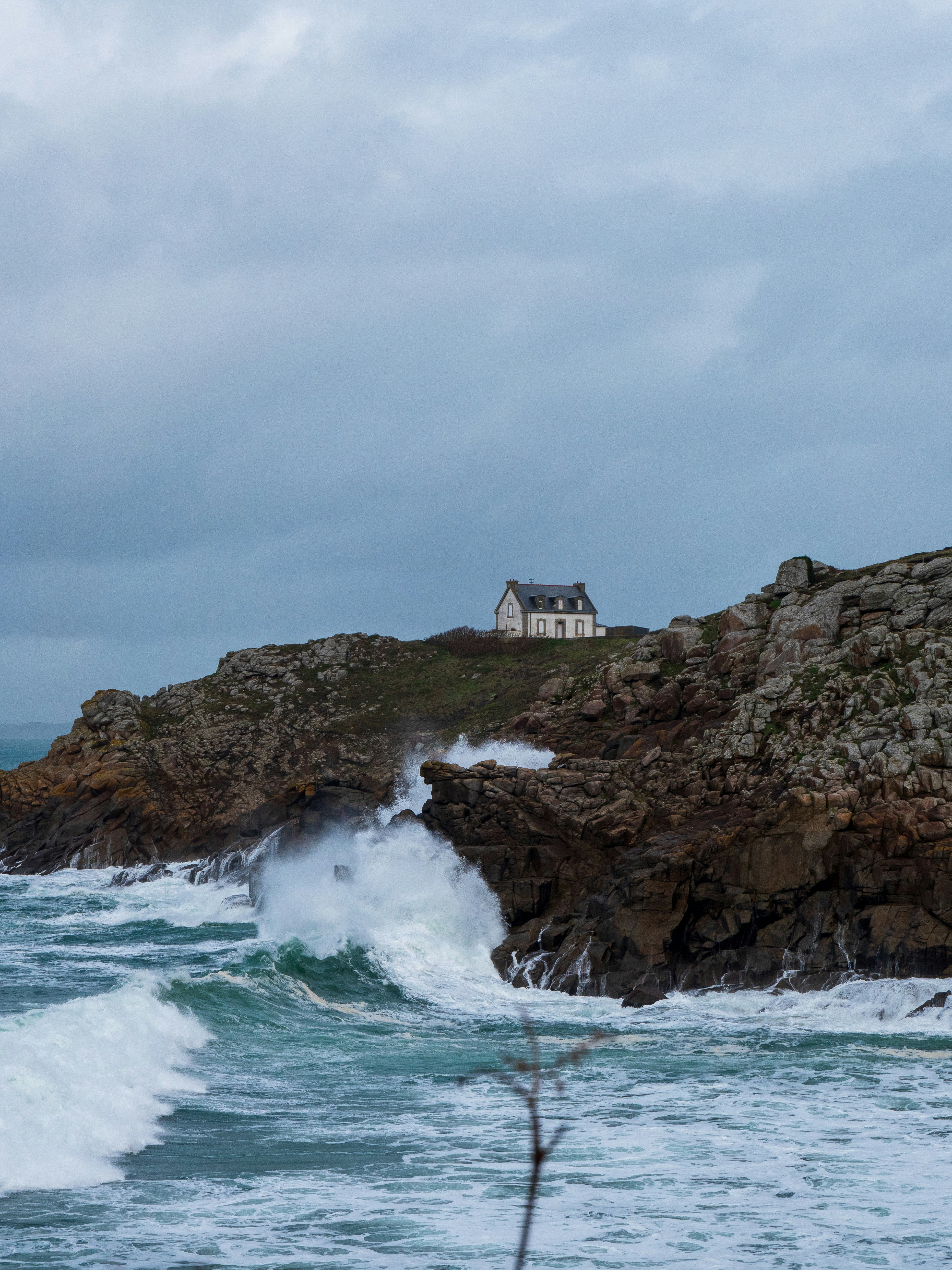 a house sitting on top of a rocky cliff next to the ocean