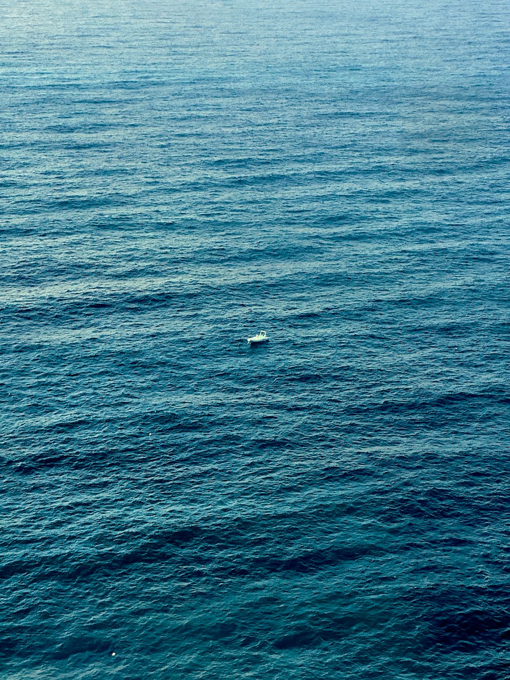 a lone boat floating in the middle of the ocean