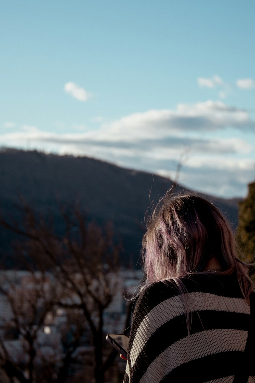 a woman with pink hair standing in front of a mountain