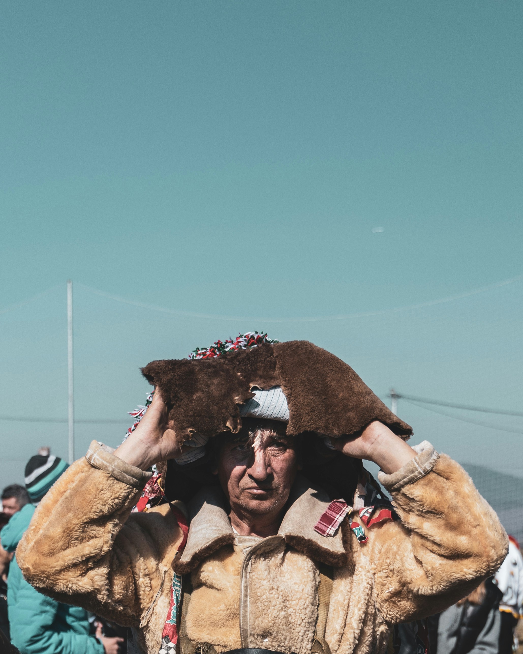 A man in a fur coat holding a stuffed animal over his head