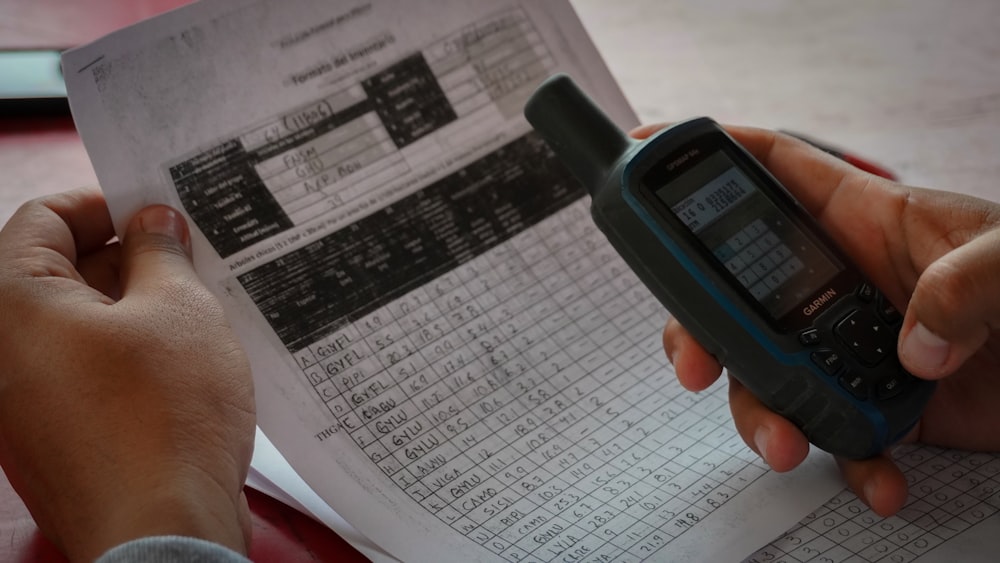 a person holding a cell phone over a piece of paper