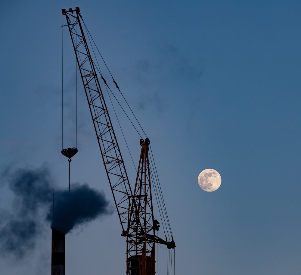 a crane is silhouetted against a full moon