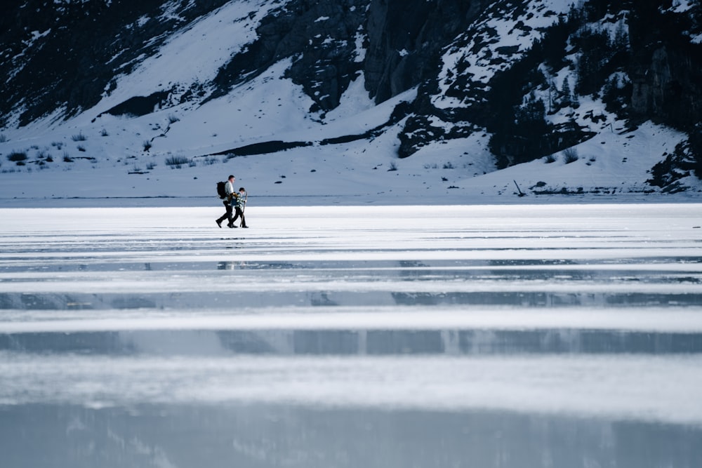 ein paar Leute, die über ein schneebedecktes Feld gehen