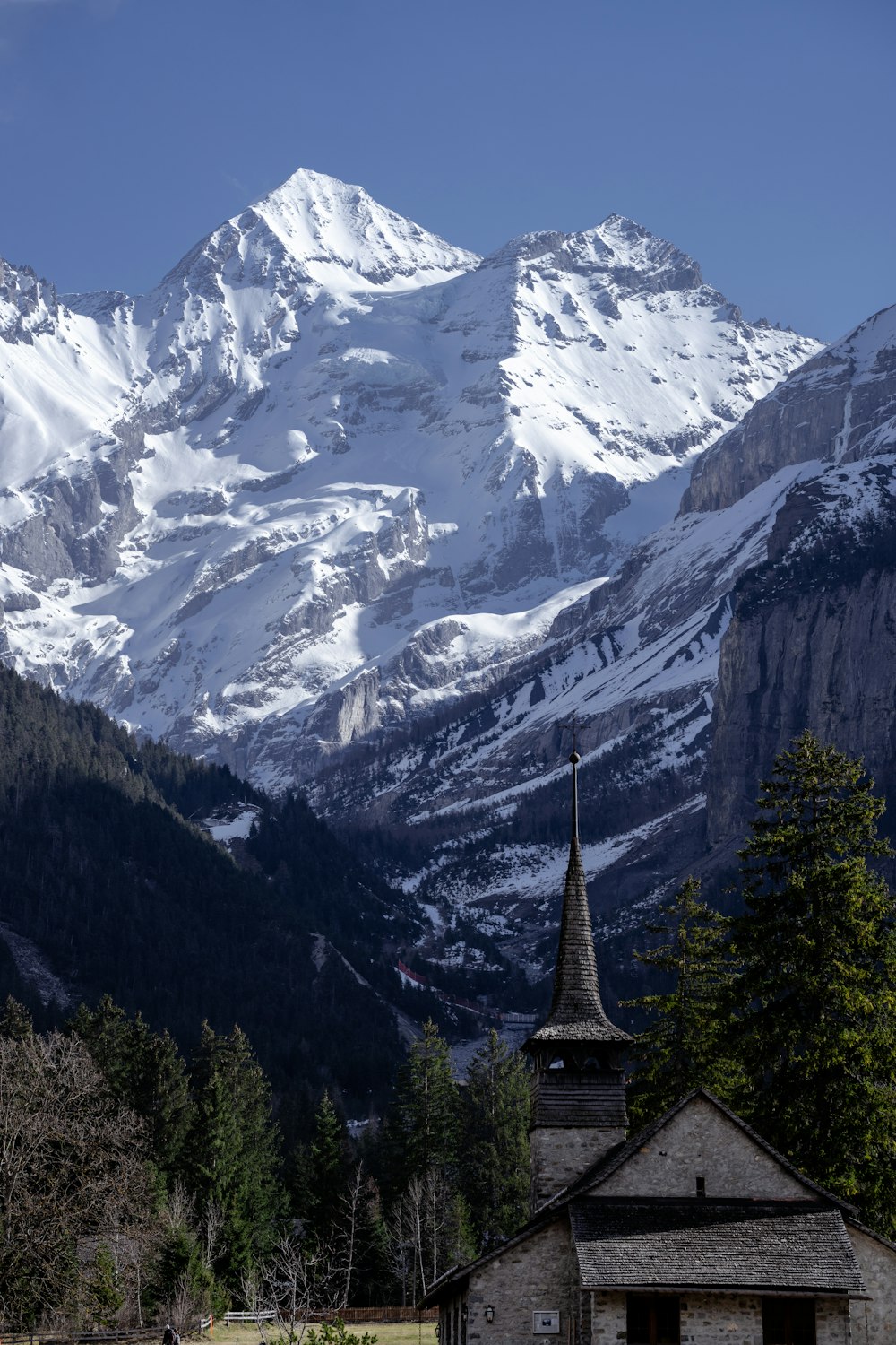 una chiesa di fronte a una catena montuosa innevata