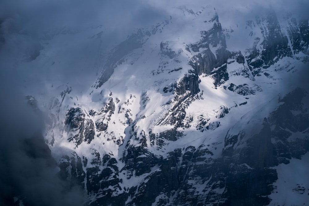 a mountain covered in snow under a cloudy sky