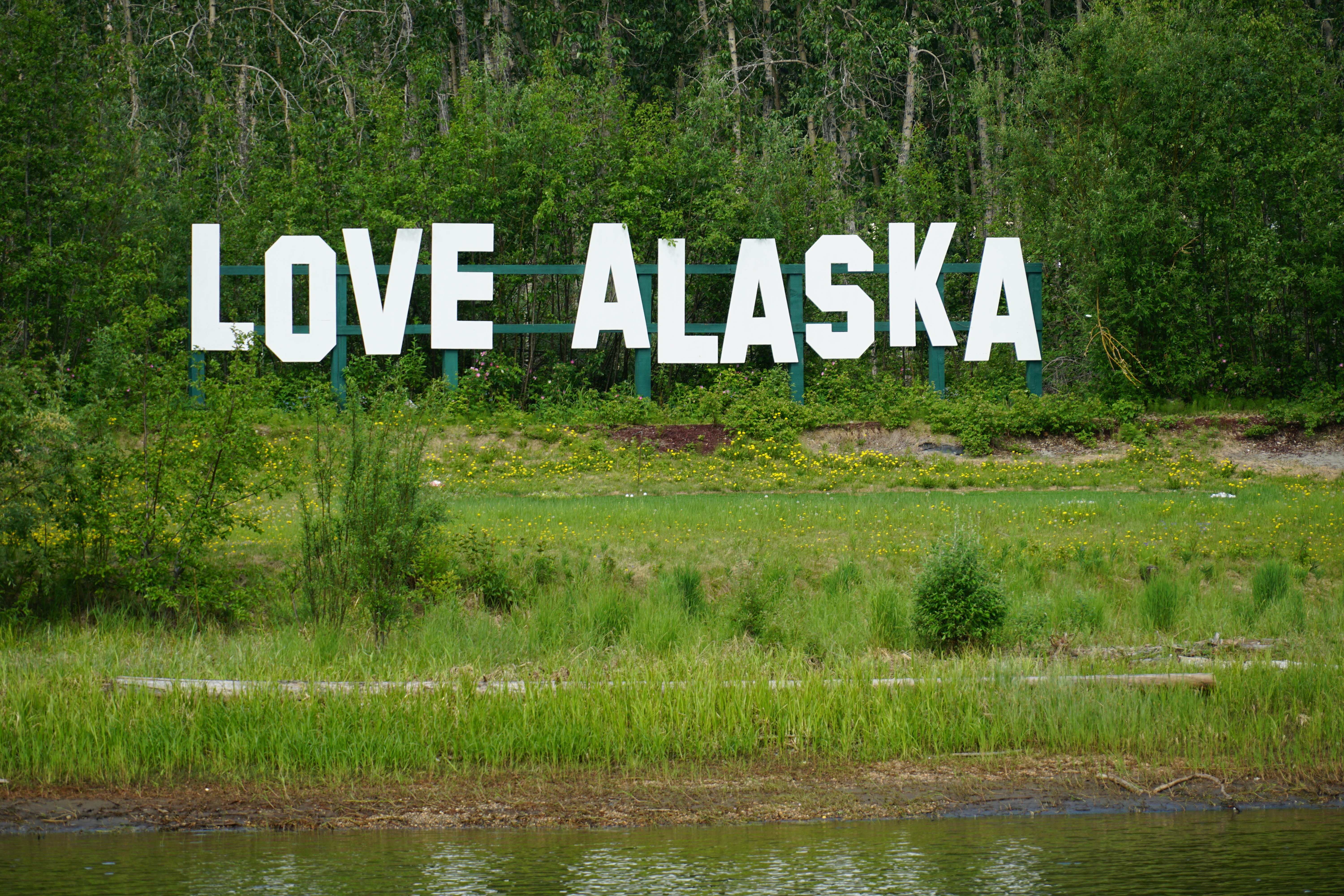 a large sign that says love alaska in front of a lake