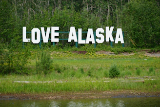 a large sign that says love alaska in front of a lake