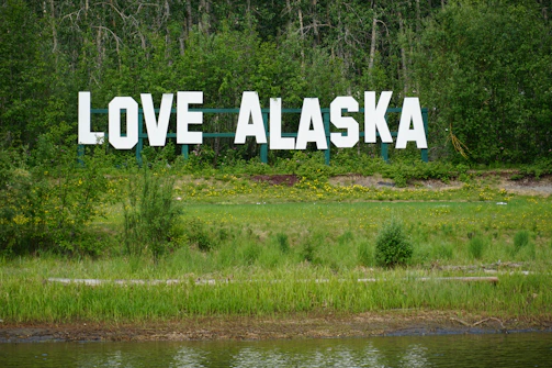 a large sign that says love alaska in front of a lake