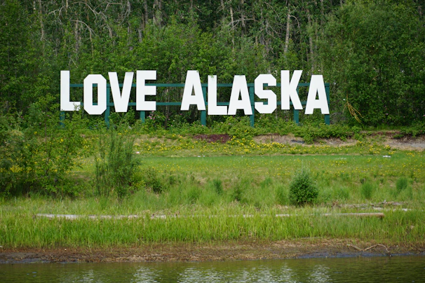 a large sign that says love alaska in front of a lake