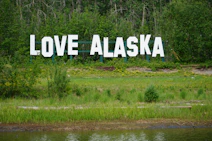 a large sign that says love alaska in front of a lake