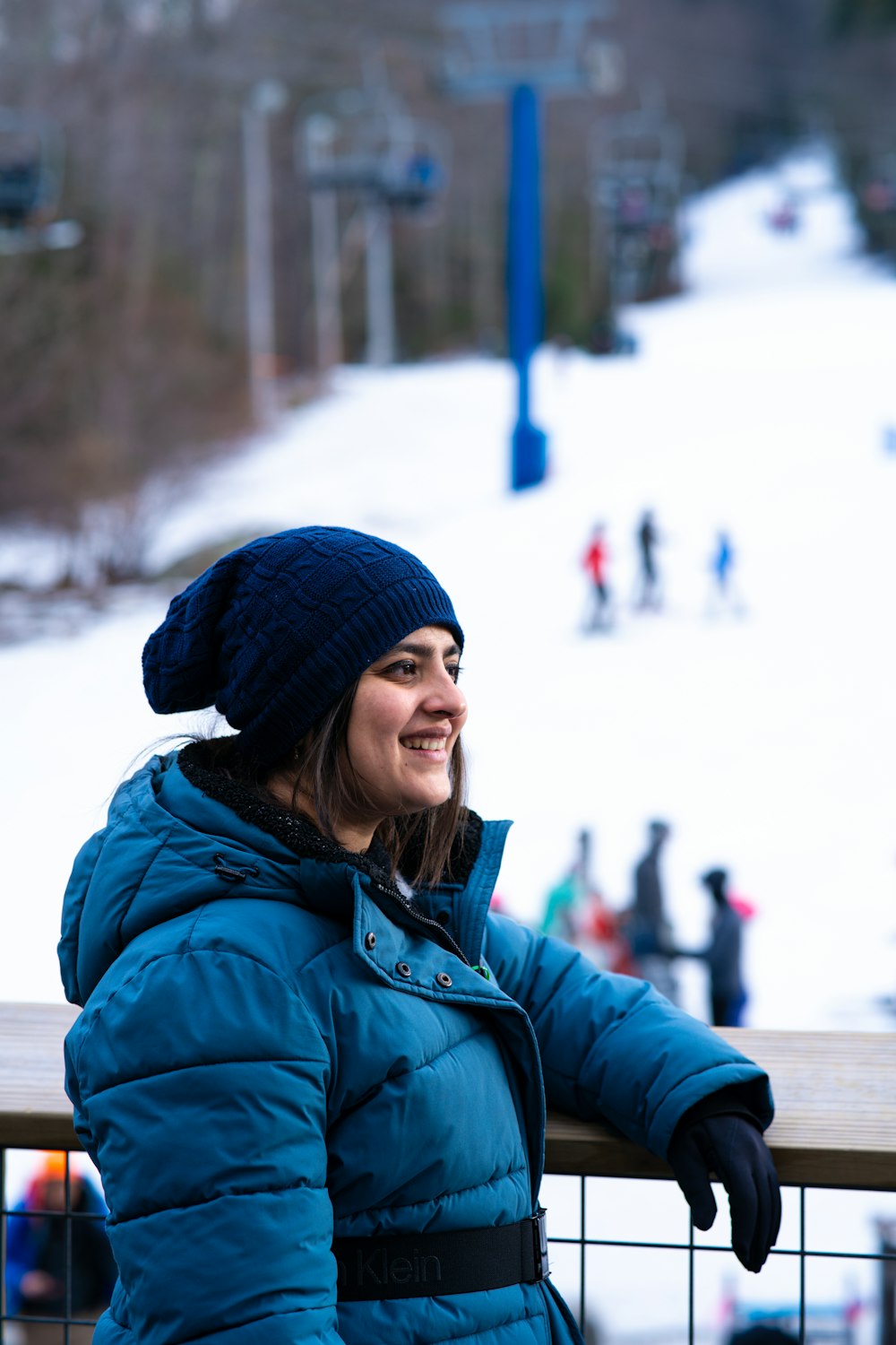 a woman in a blue jacket is standing on a balcony