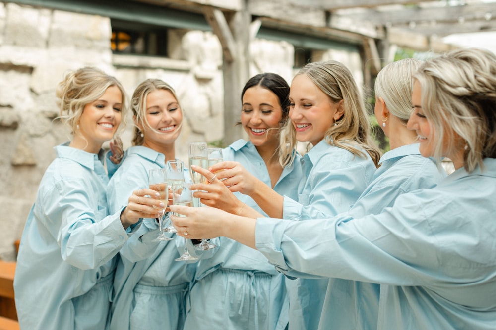 a group of women standing around each other holding wine glasses