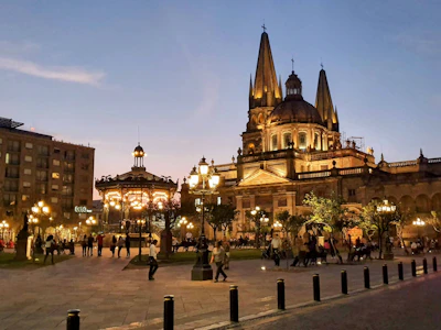 The lit cathedral towers over the plaza at dusk in Guadalajara