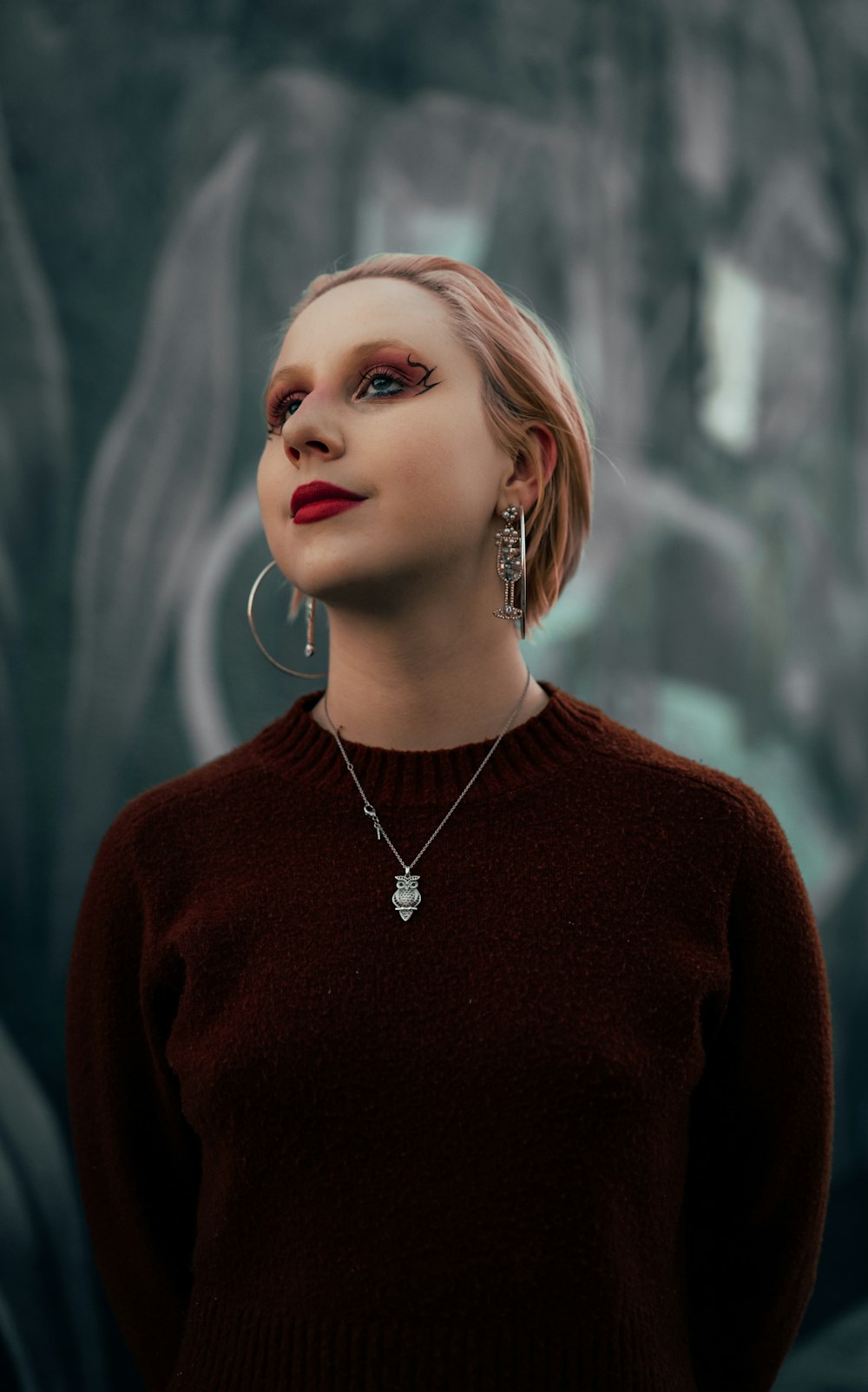 a woman wearing a brown sweater and earrings