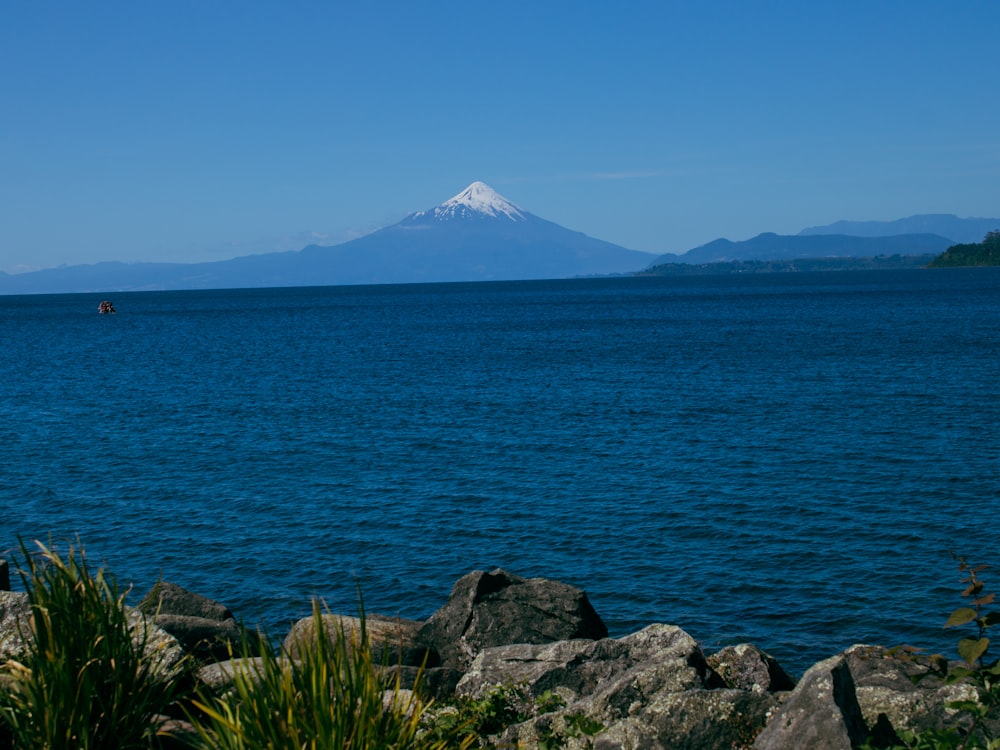 a large body of water with a mountain in the background
