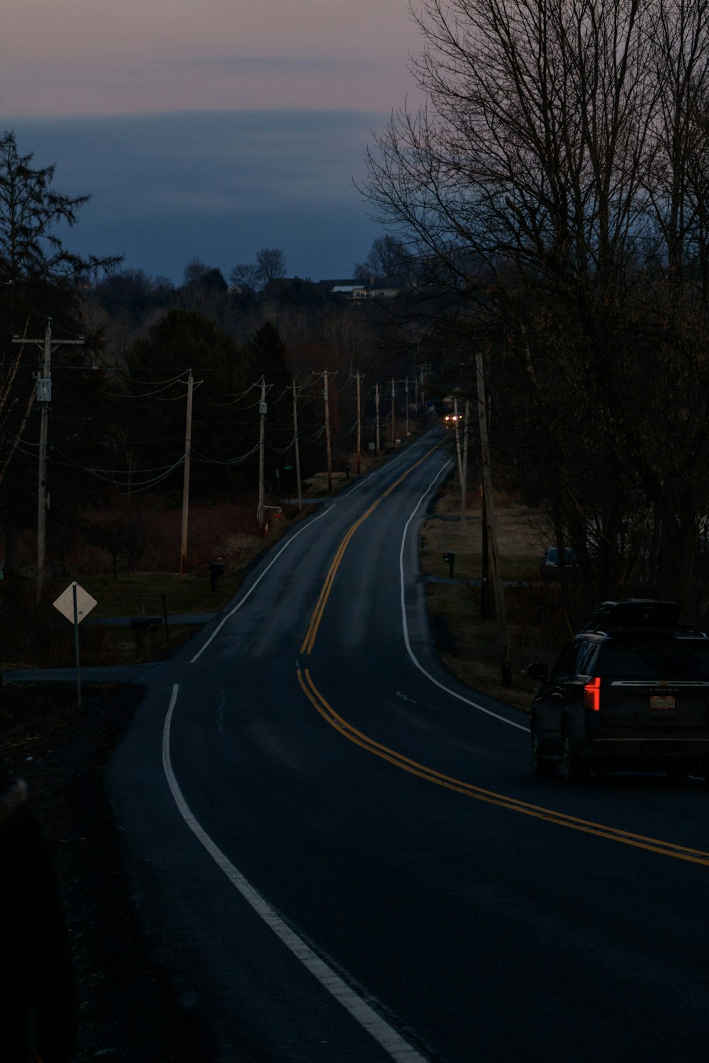 a car driving down a road at dusk