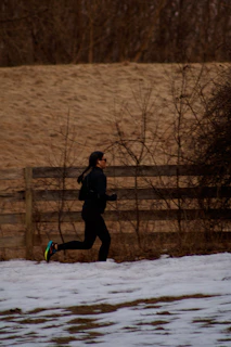 a person running in the snow near a fence