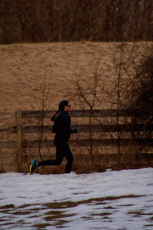 a person running in the snow near a fence