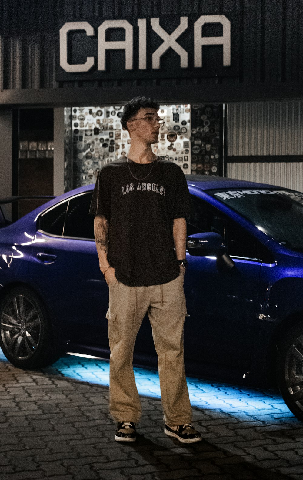 a man standing in front of a blue car