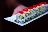 a piece of sushi with cucumber and tomatoes on it