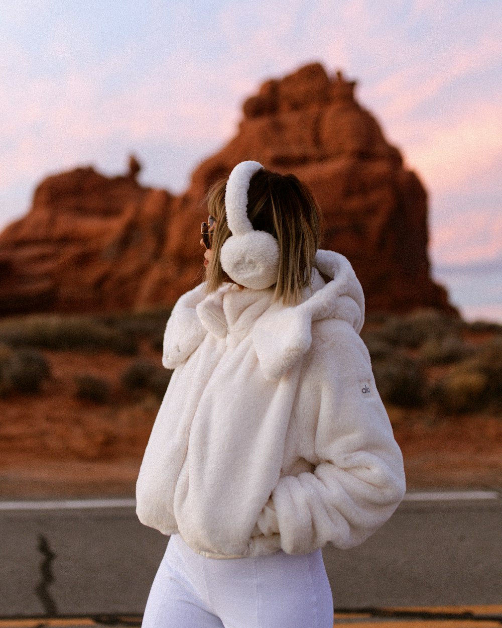 a woman wearing a white jacket and white pants