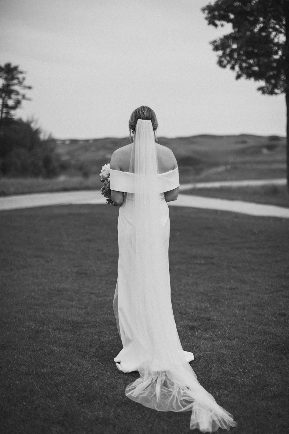a woman in a wedding dress walking across a field