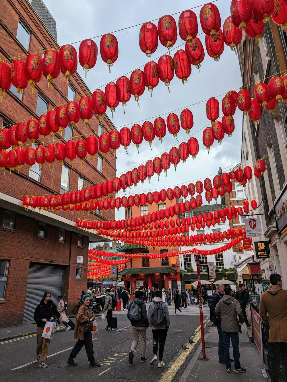 a group of people walking down a street under red lanterns