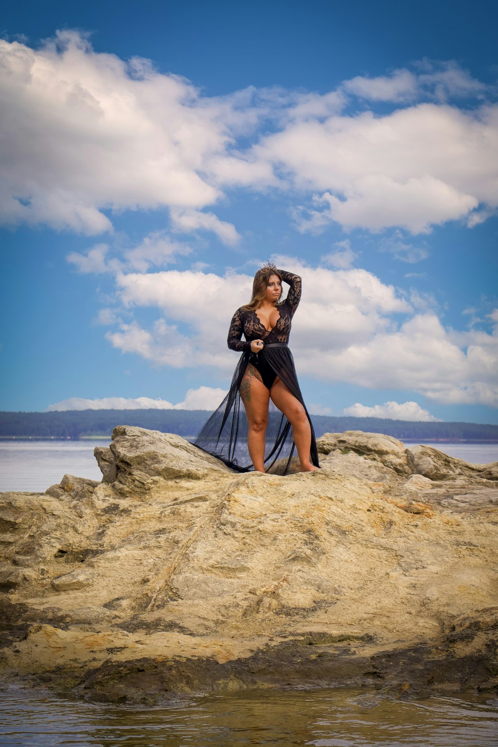 a woman is standing on a rock by the water