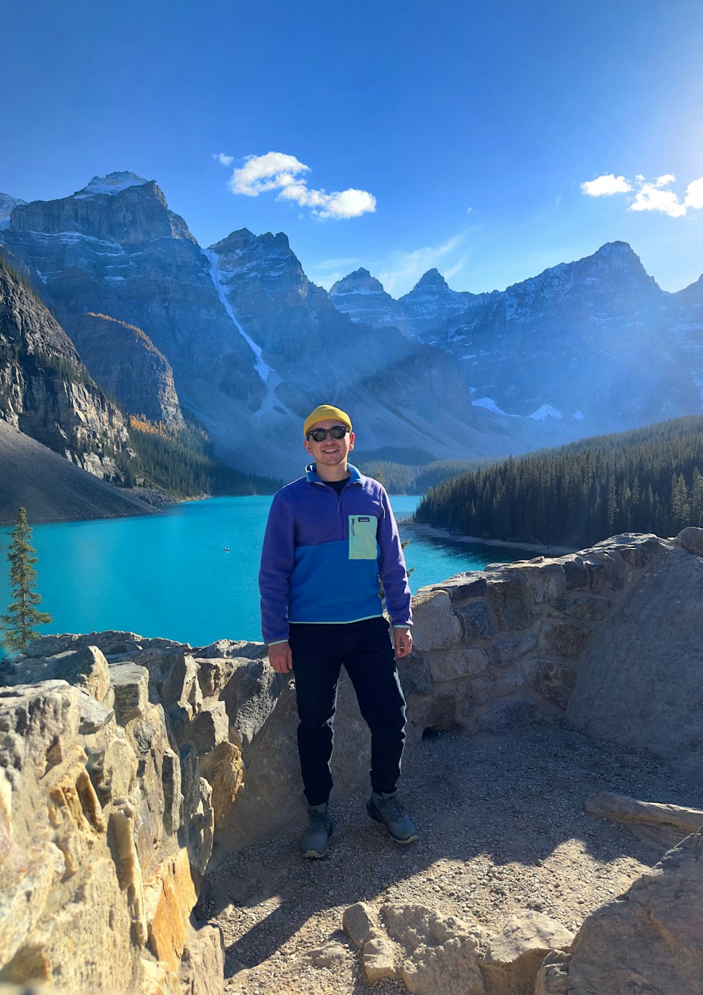 a man standing on top of a mountain next to a lake