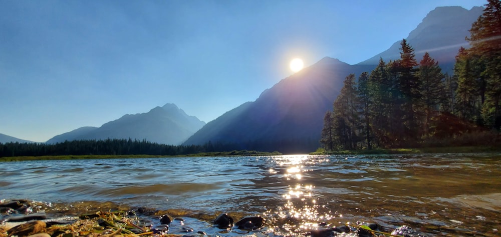 the sun shines brightly over a mountain lake