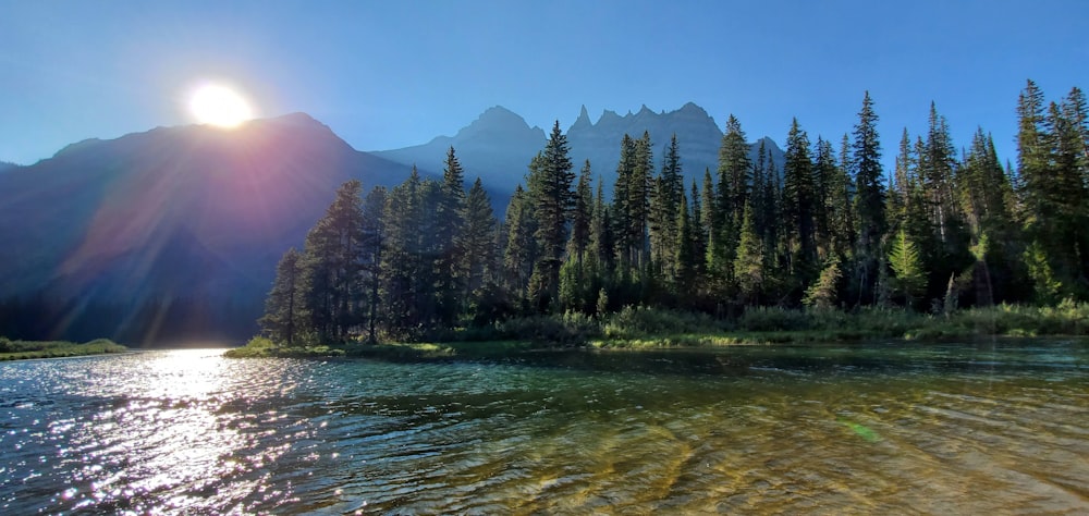 the sun shines brightly on a mountain lake