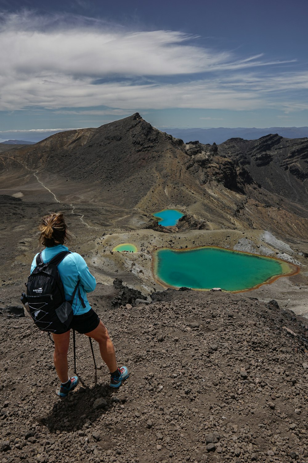 a woman standing on top of a mountain looking at a lake