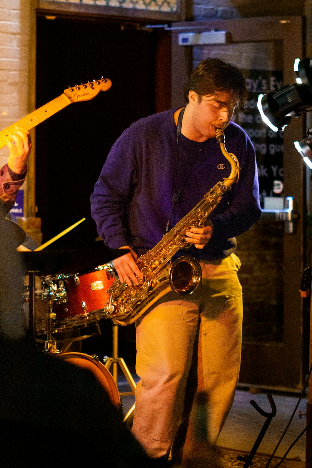 Un hombre tocando un saxofón frente a una guitarra