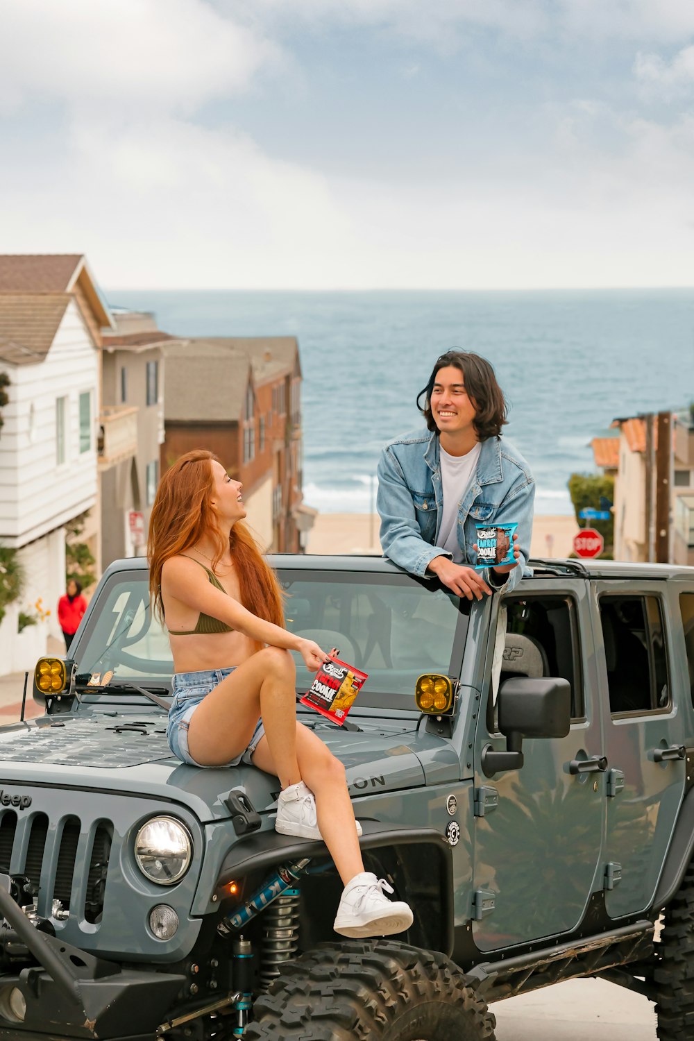 a woman sitting on top of a jeep next to a man