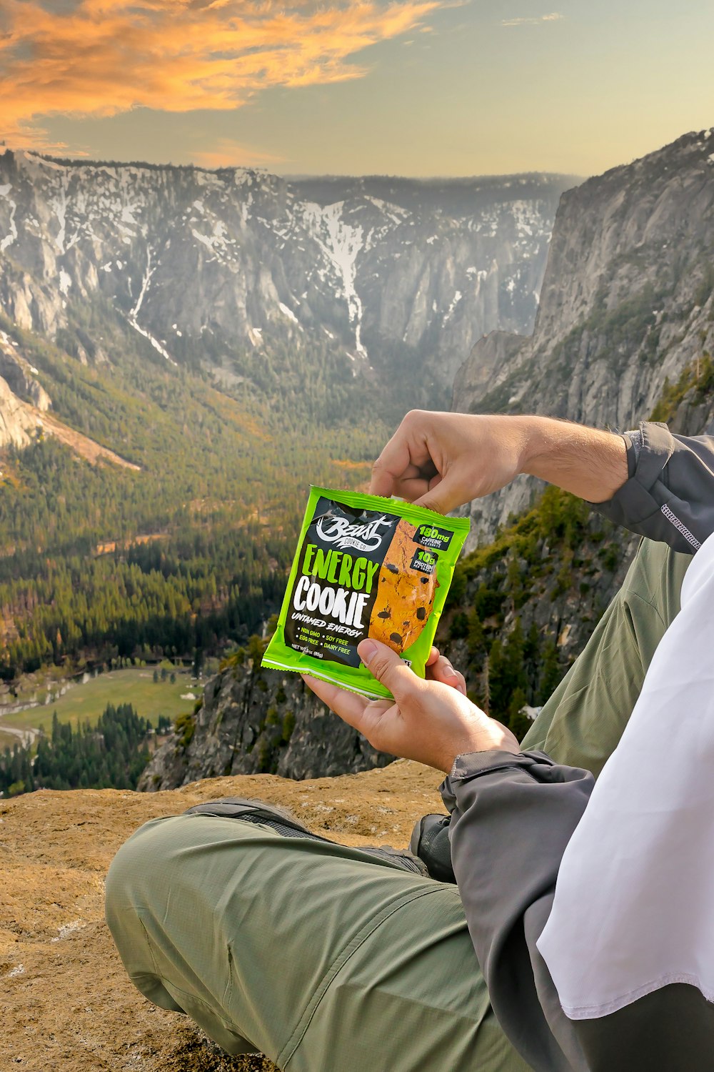 a man sitting on a mountain holding a package of food
