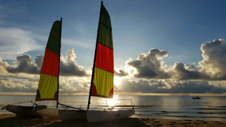 a couple of sail boats sitting on top of a beach