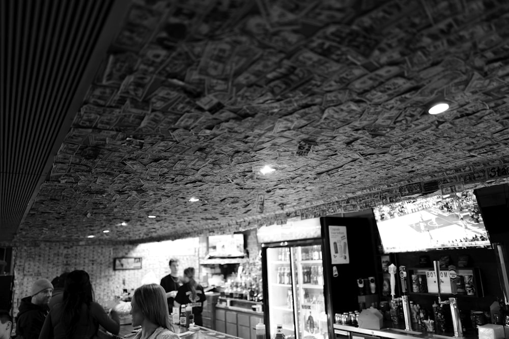 a black and white photo of people sitting at a bar