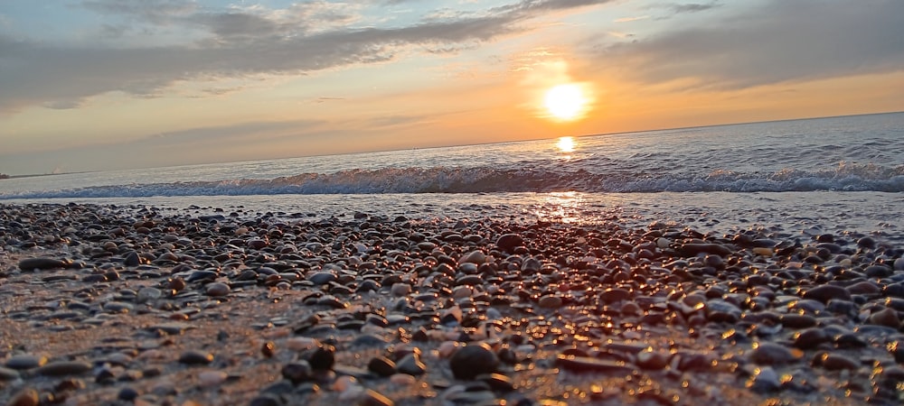 the sun is setting over the ocean on the beach